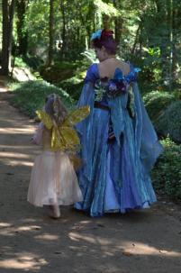A queen and a wee faery wander in the garden.
